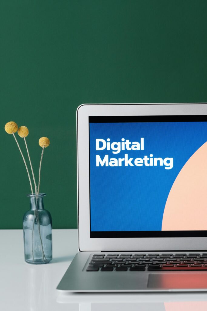 pexels-photo-6483583-6483583 A laptop displaying 'Digital Marketing' with a minimalist floral decor in a glass vase.